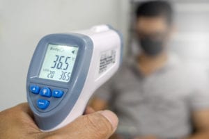 Taking employees temperature with infrared thermometer